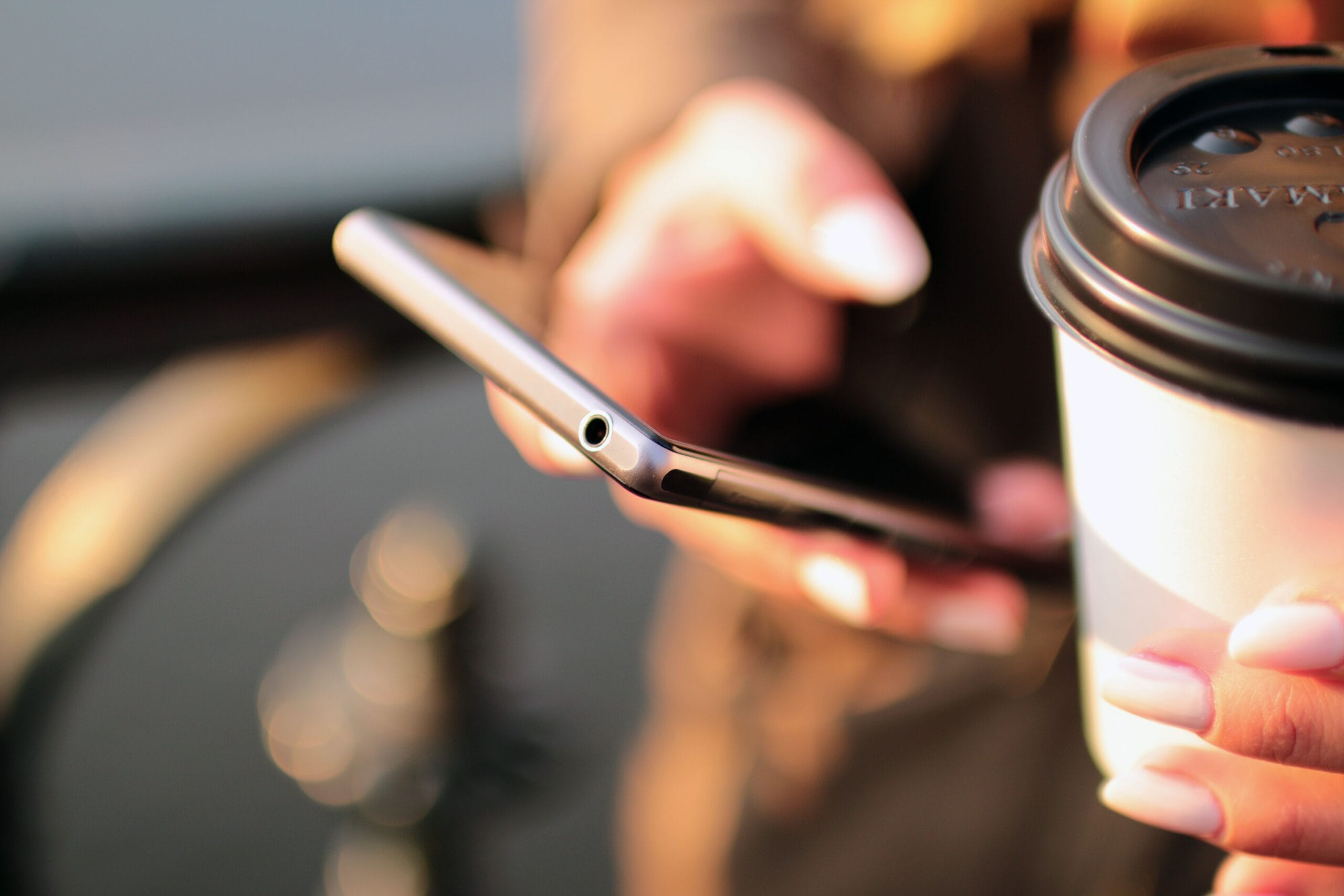 Close-up of a person using a smartphone to answer questionnaire screeners with coffee cup on table