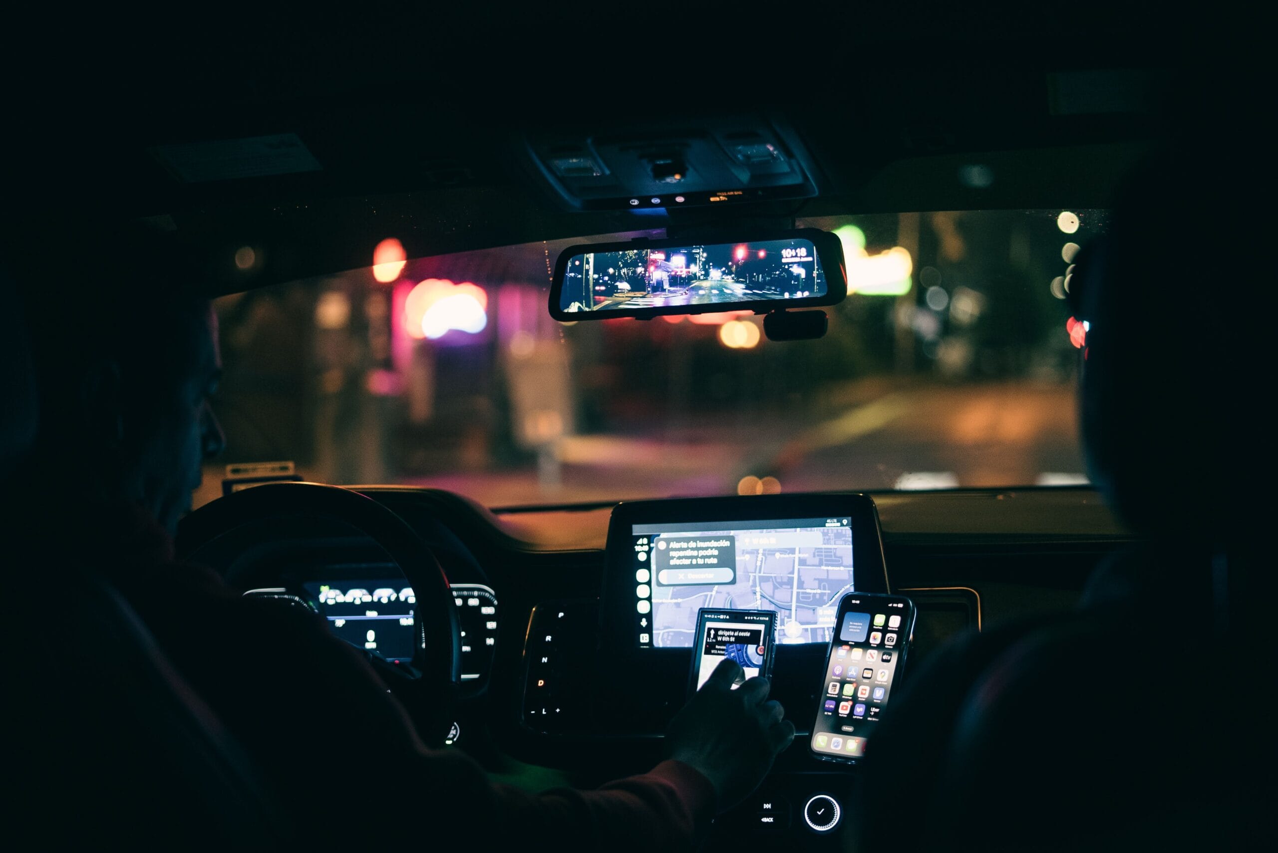 driver looking at smartphone with navigation app open, city streets at dusk