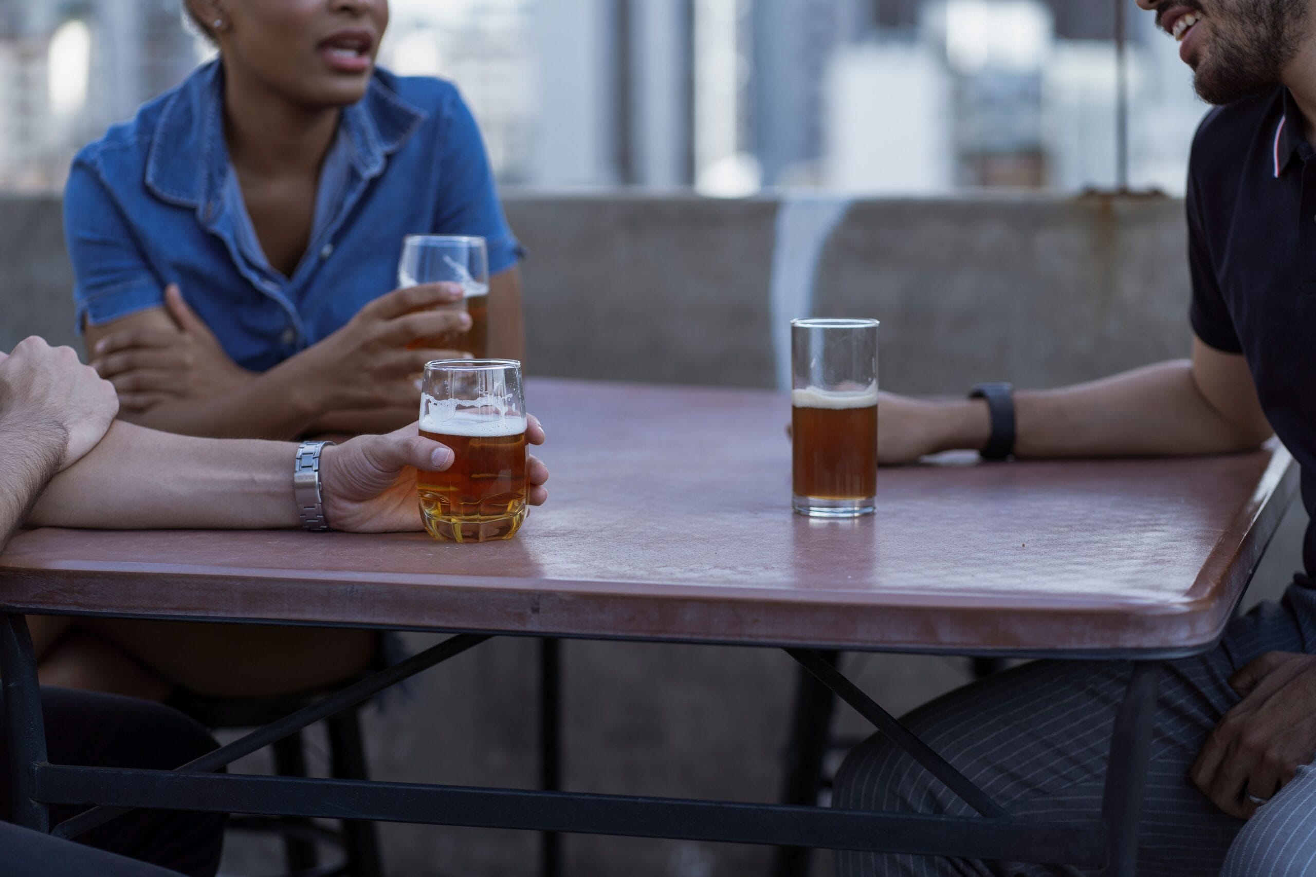A relaxed group of friends clinking beers on a patio at sunset
