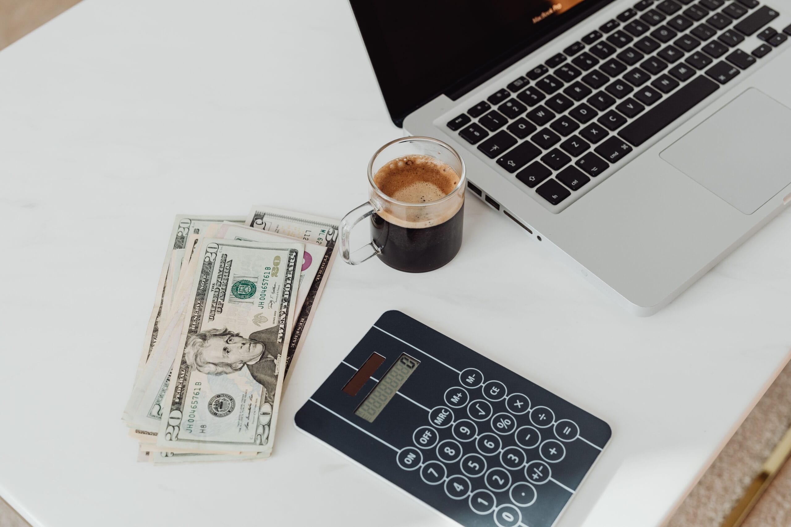 close‑up of a laptop with financial charts and a coffee mug on a wooden desk