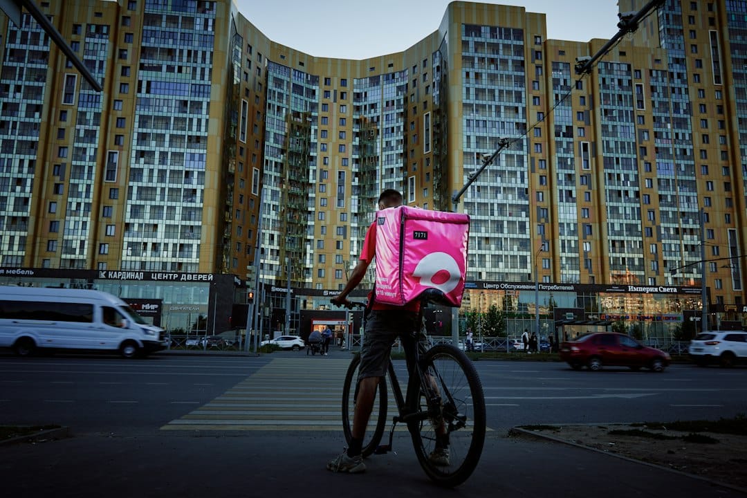 A smiling delivery driver holding a insulated bag on a city street