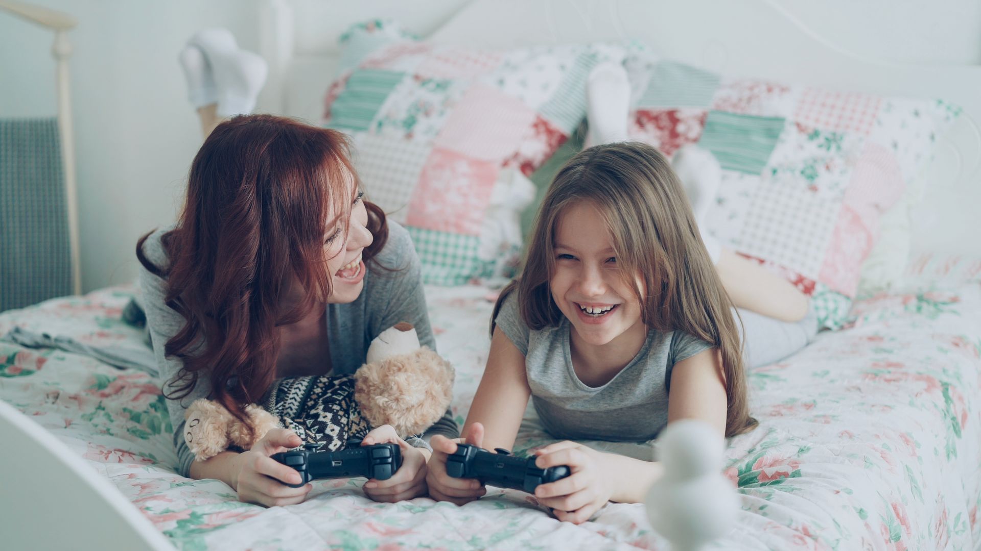 Get Paid to Play Games: 6 Legit Apps to Try 1 A mother and daughter laughing and playing video games in a cozy bedroom.