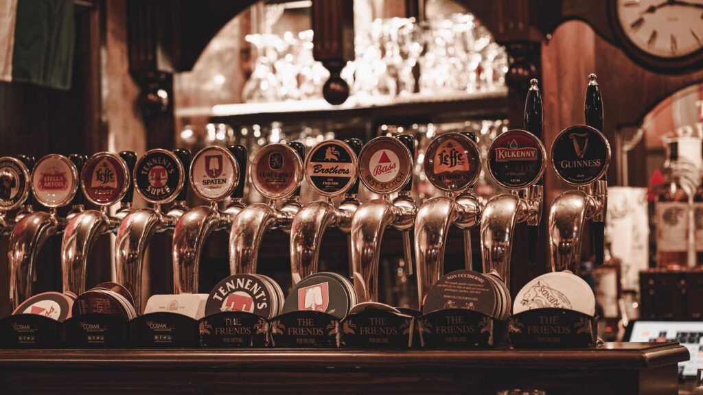 Best Beer Brands in India: Popular Indian & International Choices (2026) 3 A row of vintage beer taps serving classic brews in a Milan pub.