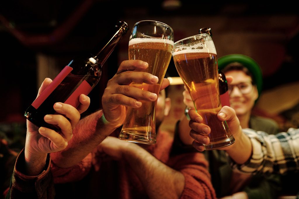 Types of Beer in India: Lager, Ale, IPA, Wheat Beer & More 2 Cheerful group of friends toasting with beer glasses in a lively pub setting