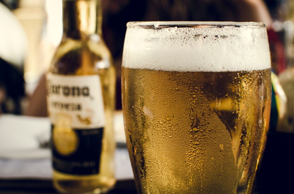 Best Beer Brands in India: Popular Indian & International Choices (2026) 2 Close-up of chilled beer with frothy head next to a bottle on a bar table.