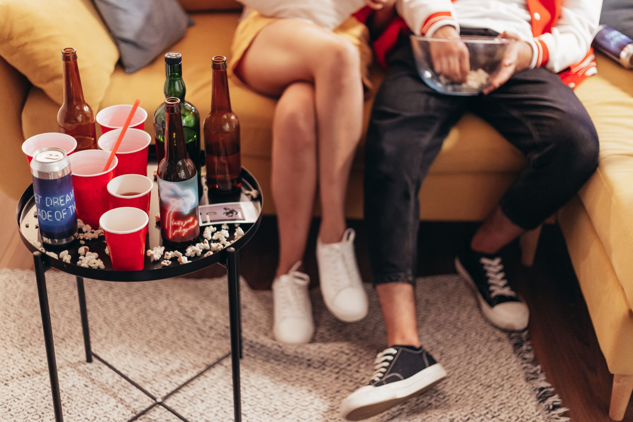 A lively living‑room super bowl party with friends cheering and drinks on a coffee table