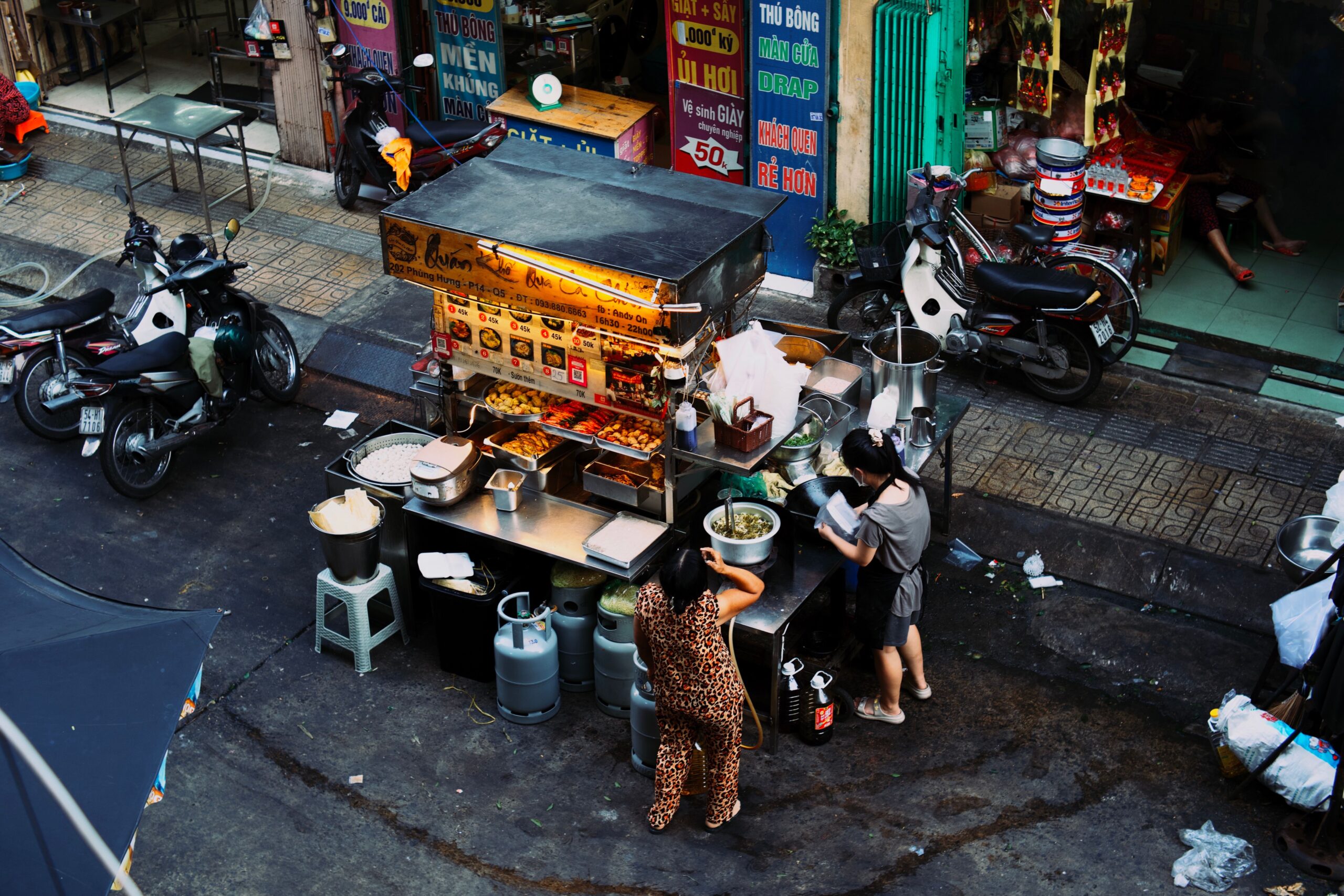 Bustling outdoor food market stall serving local street snacks and affordable draft beers